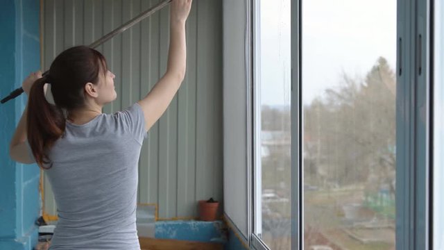 Young woman washing windows with rubber mop.