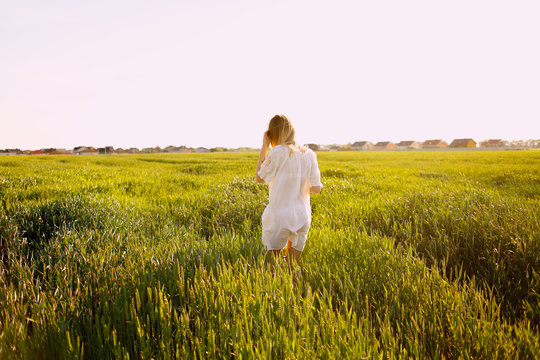 Hello, June! The concept of summer. Girl on the field with green wheat, welcomes the first day of summer