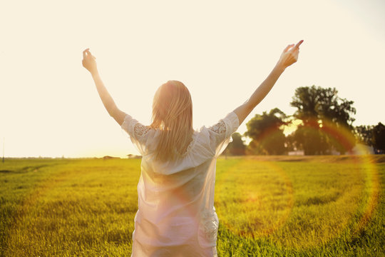 Hello, June! The concept of summer. Girl on the field with green wheat, welcomes the first day of summer