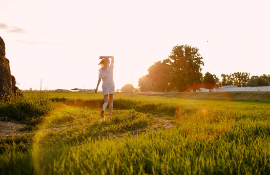 Hello, June! The concept of summer. Girl on the field with green wheat, welcomes the first day of summer