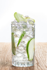 Glass of cold apple lemonade with ice on wooden table