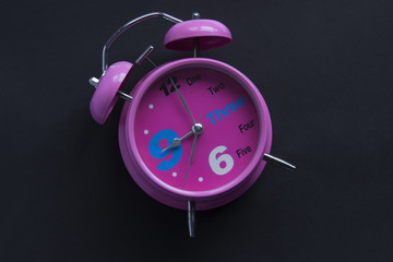 Pink alarm clock on dark background