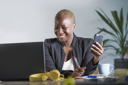 Happy Successful Black Afro American Woman In Business Jacket Working Cheerful At Office Laptop Taking Notes Using Mobile Phone