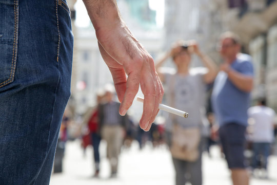 Close up image of young man smoking a cigarette on the street