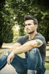 Obraz premium Handsome muscular man with tattoo posing in European luxury garden in Turin, Italy