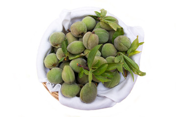 Fresh almonds inside a wicker basket on a white background seen from above