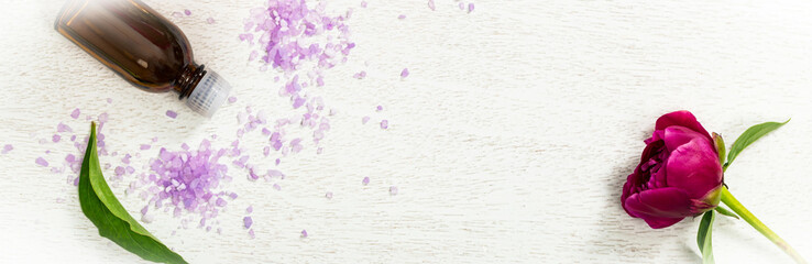Bottle of Essential Oil Spa Theme Objects with Fresh Peony Flowers Panoramic image. Selective focus.