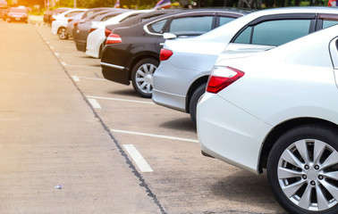 Closeup of rear side of white car and other cars park in parking area beside the street.