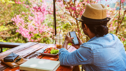 Asian man travel nature. Travel relax. Hands are holding the phone.