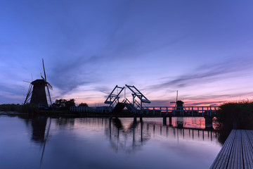 Fototapeta na wymiar Kinderdijk Windmühlen mit Brücke nach Sonnenuntergang