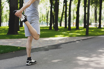 Unrecognizable fitness man stretching legs outdoors