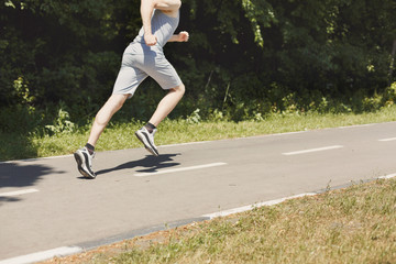 Young man jogging on treadmill in park, copy space