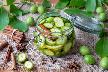 A glass jar filled with unripe walnuts, lemon and cinnamon