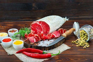 Sliced cured coppa with spices and a sprig of rosemary.