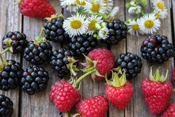 Raspberry and blackberry on a wooden background. Sweets and delicious summer berries.