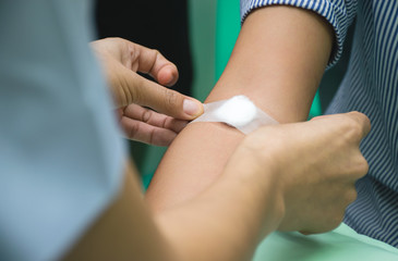 Nurse is applying the bandaid to cover the wound or give a pressure to stop bleeding