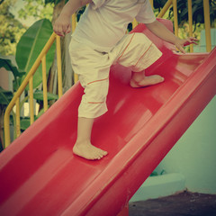 part of boy playing on slide in tropical resort. image with warm vintage toning