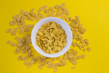Corn flakes in a plate on a yellow background