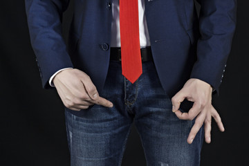 Man in suit businessman holding on inguinal area and showing gesture class, black background