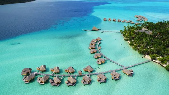 Aerial view of Motu Tautau, palm trees on little islets and turquoise water of blue lagoon, over water bungalows, tropical paradise of South Pacific Ocean - Tahaa island, seascape of French Polynesia
