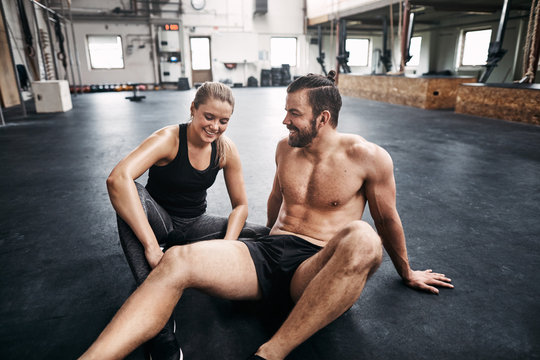 Two people resting resting on a gym floor after exercising