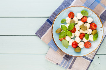 Delicious caprese salad with ripe cherry tomatoes and mini mozzarella cheese balls with fresh basil leaves.