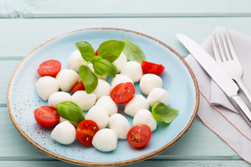Delicious caprese salad with ripe cherry tomatoes and mini mozzarella cheese balls with fresh basil leaves.