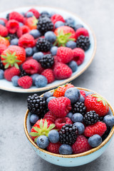 Fresh berry salad on blue dishes. Vintage wooden background.