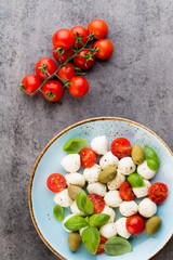 Delicious caprese salad with ripe cherry tomatoes and mini mozzarella cheese balls with fresh basil leaves.
