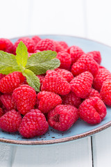 Fresh raspberries in a plate on a  vintage background.