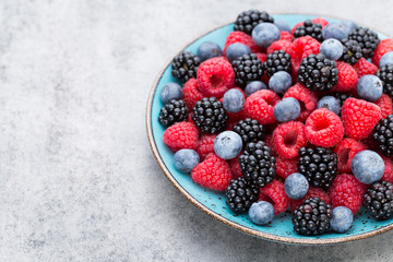 Fresh berry salad on blue dishes. Vintage wooden background.