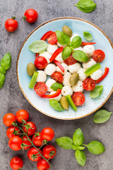 Delicious caprese salad with ripe cherry tomatoes and mini mozzarella cheese balls with fresh basil leaves.