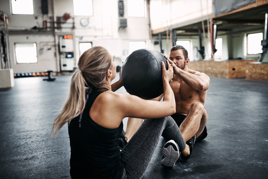 Two people exercising with a medicine ball at the gym