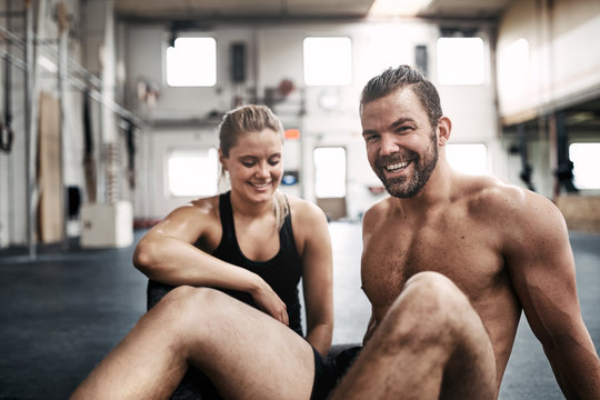 Smiling young couple resting after working out at the gym