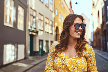 Smiling young woman wearing sunglasses exploring city streets