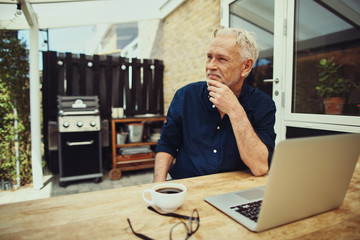 Content senior man sitting on his patio using a laptop