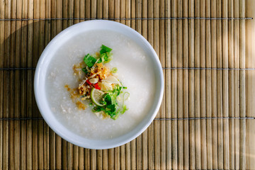 Thai style rice congee or rice porridge with ingredient condiments. (Fish sauce,fried garlic,chilli,pepper, spring onion, coriander and lime).