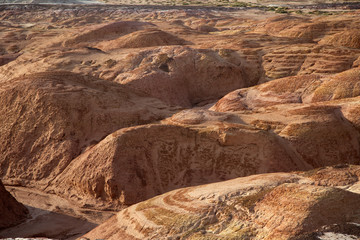 Multicolored red, orange and yellow striped hills with saline soil under a bright blue sky in Eastern Kazakhstan