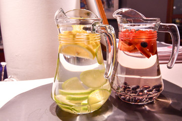 Two jugs of fresh fruit in water creating home made helthy fruit juice