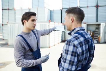 Obraz premium One of loader men explaining his colleague where should boxes be carried