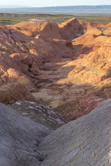 Multicolored red, orange and yellow striped hills with saline soil under a bright blue sky in...