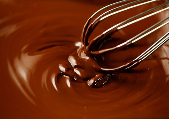 Chocolate. Mixing melted dark chocolate with a whisk. Closeup of liquid hot chocolate swirl. Confectionery