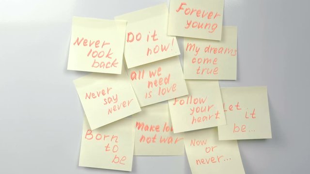 Motivation phrases on yellow sticker paper sheets on a white board.
