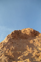 Uneven multicolored red, orange and yellow striped hills under a bright blue sky in Eastern Kazakhstan, vertical
