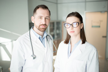 Two young clinicians in whitecoats looking at camera in contemporary clinics
