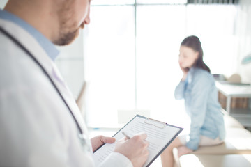 Modern clinician writing down prescriptions for one of his patients