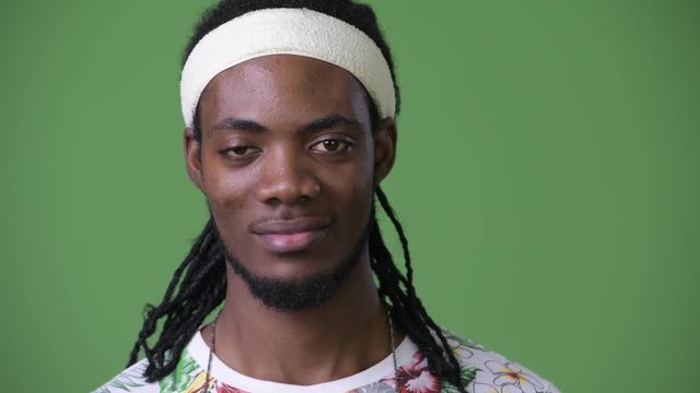 Young handsome African man with dreadlocks against green background