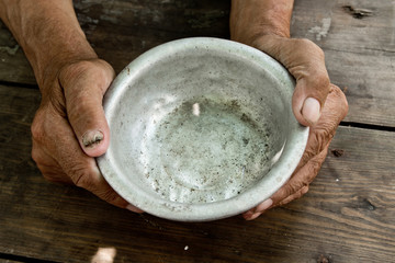 The poor old man's hands hold an empty bowl of beg you for help. The concept of hunger or poverty. Selective focus. Poverty in retirement. Alms - obrazy, fototapety, plakaty