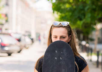 PORTRAIT OF YOUNG GIRL WHILE HOLDING HER SKATEBOARD
