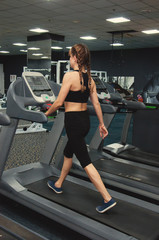 Fototapeta na wymiar Fitness woman is engaged on a treadmill in the gym. Rear view and side view.